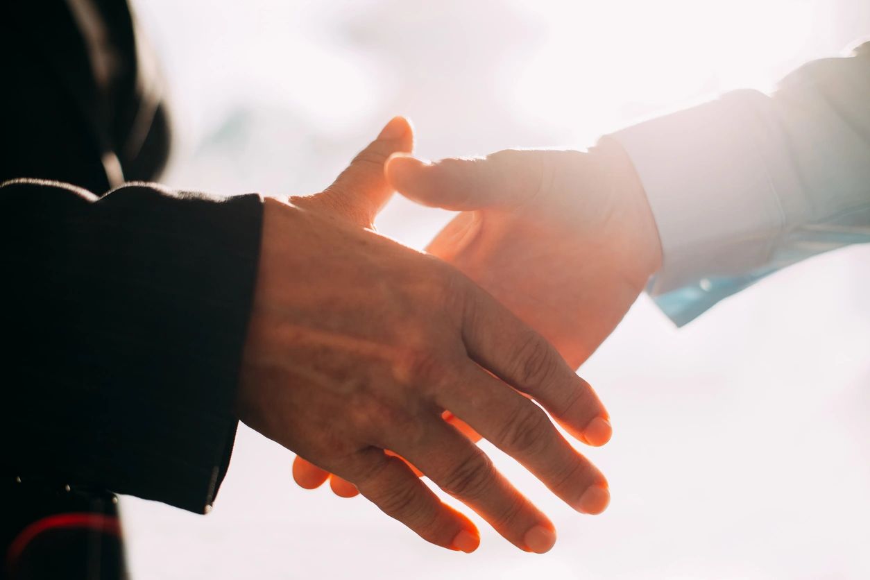 Two people shaking hands at golden hour, representing partnership and trust